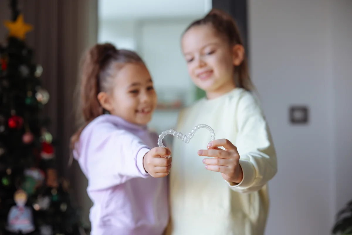 Can kids have Invisalign First? A child holding an Invisalign® First clear aligner